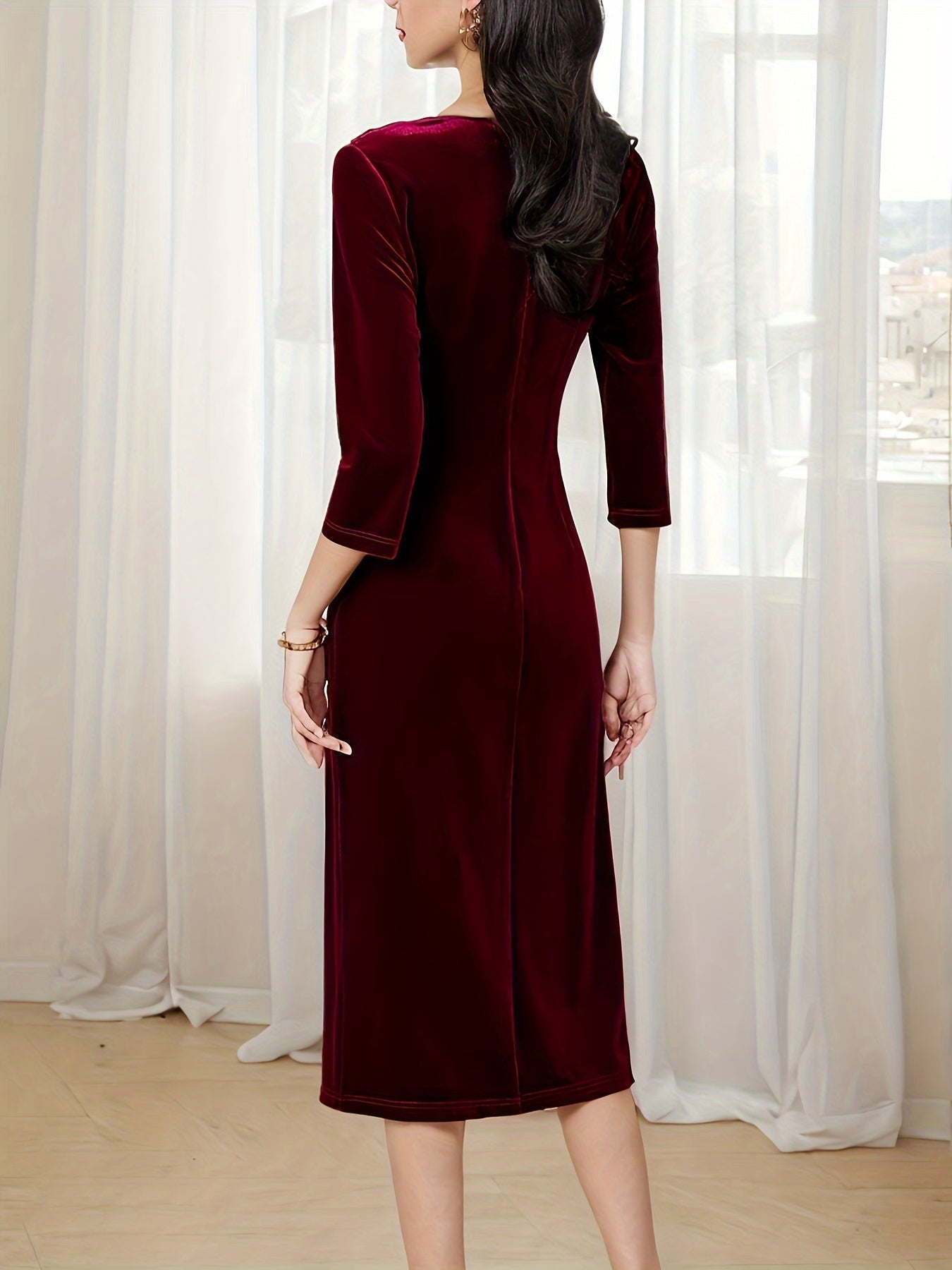 Back view of a burgundy velvet midi dress with three-quarter sleeves and a sleek fit