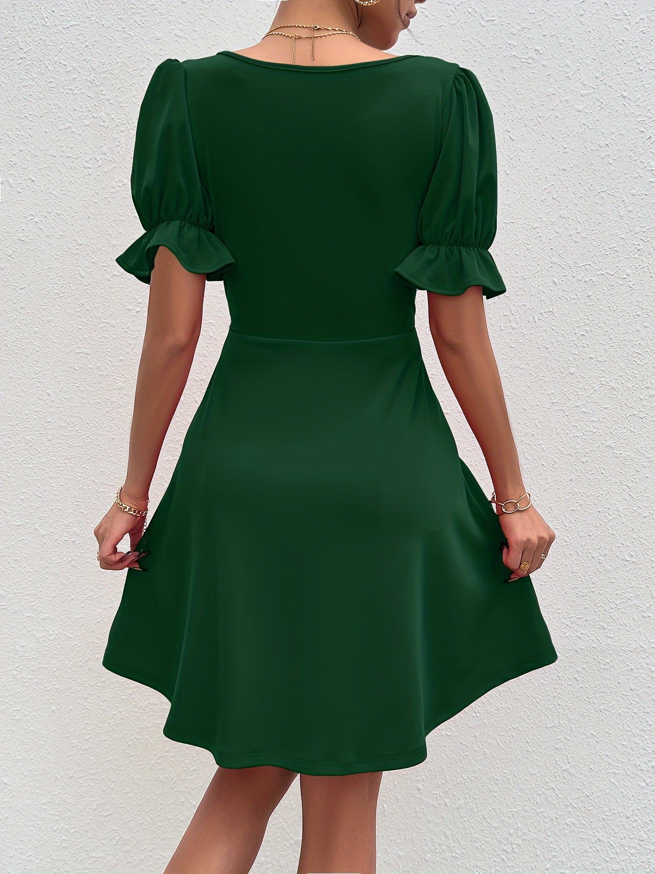 Back view of an elegant puff sleeve dress in dark green with a flattering fit and flared skirt