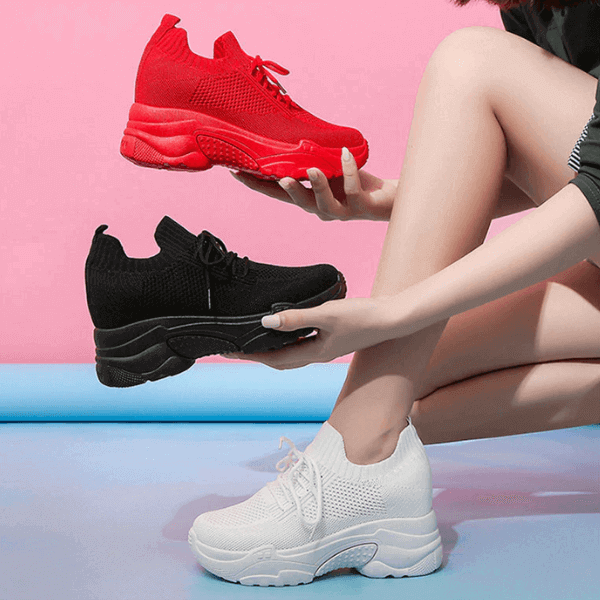 Luxury women's sneakers in red black and white with chunky soles held by a woman in sporty attire