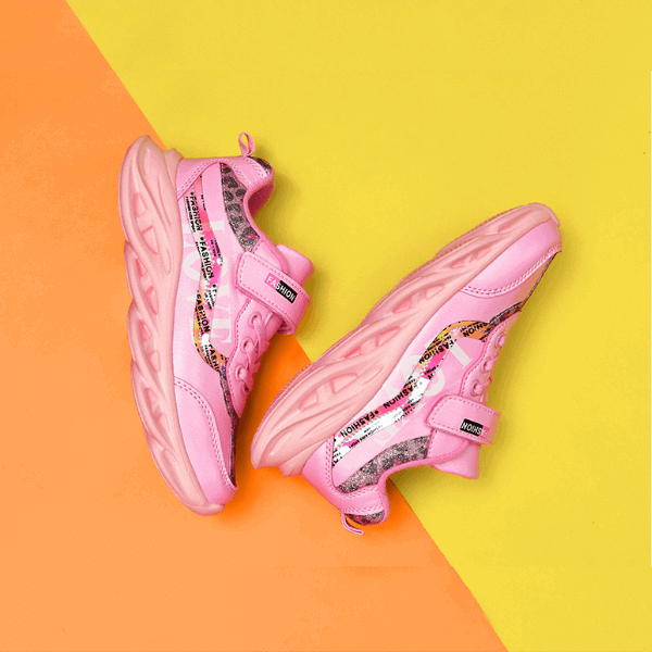 Pair of stylish pink luxury girls shoes with chunky soles on orange and yellow background