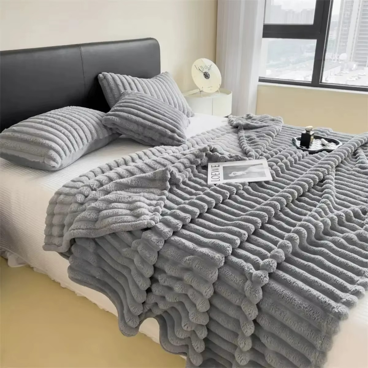 Cozy soft plush velvet blanket in grey, draped over a bed with matching pillows for a stylish look